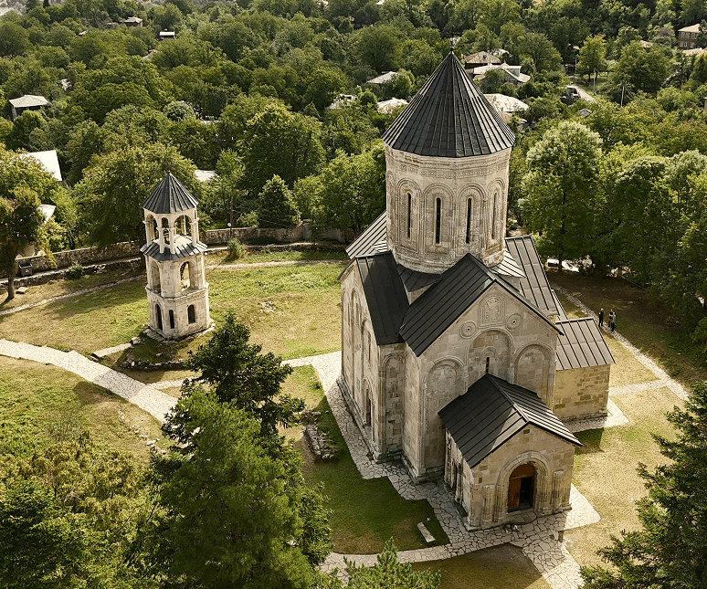 Ancient church bells with snow-capped Greater Caucasus peaks in the background